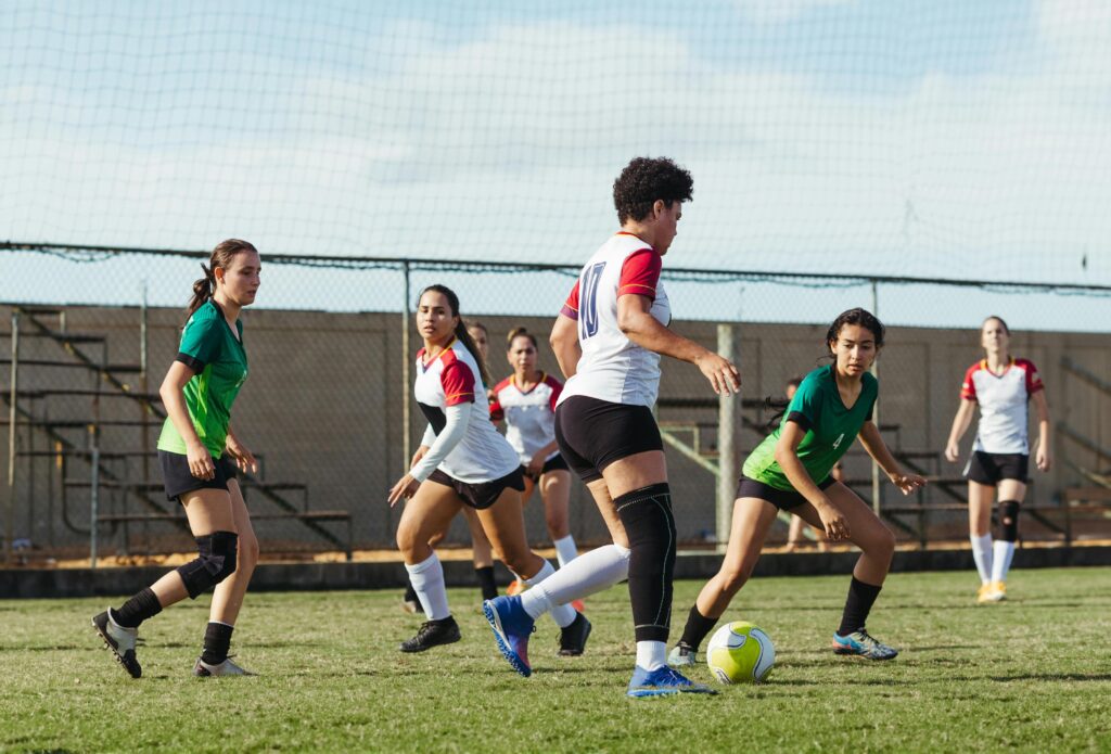 Women soccer players in intense action during a sunny outdoor match, showcasing teamwork and athletic skills.
